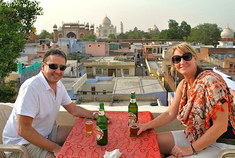 Mature travelers relaxing on a rooftop bar enjoying sunset views of the magnificent Taj Mahal UNESCO site in Agra, India, close to Agra Fort and Keoladeo National Park.