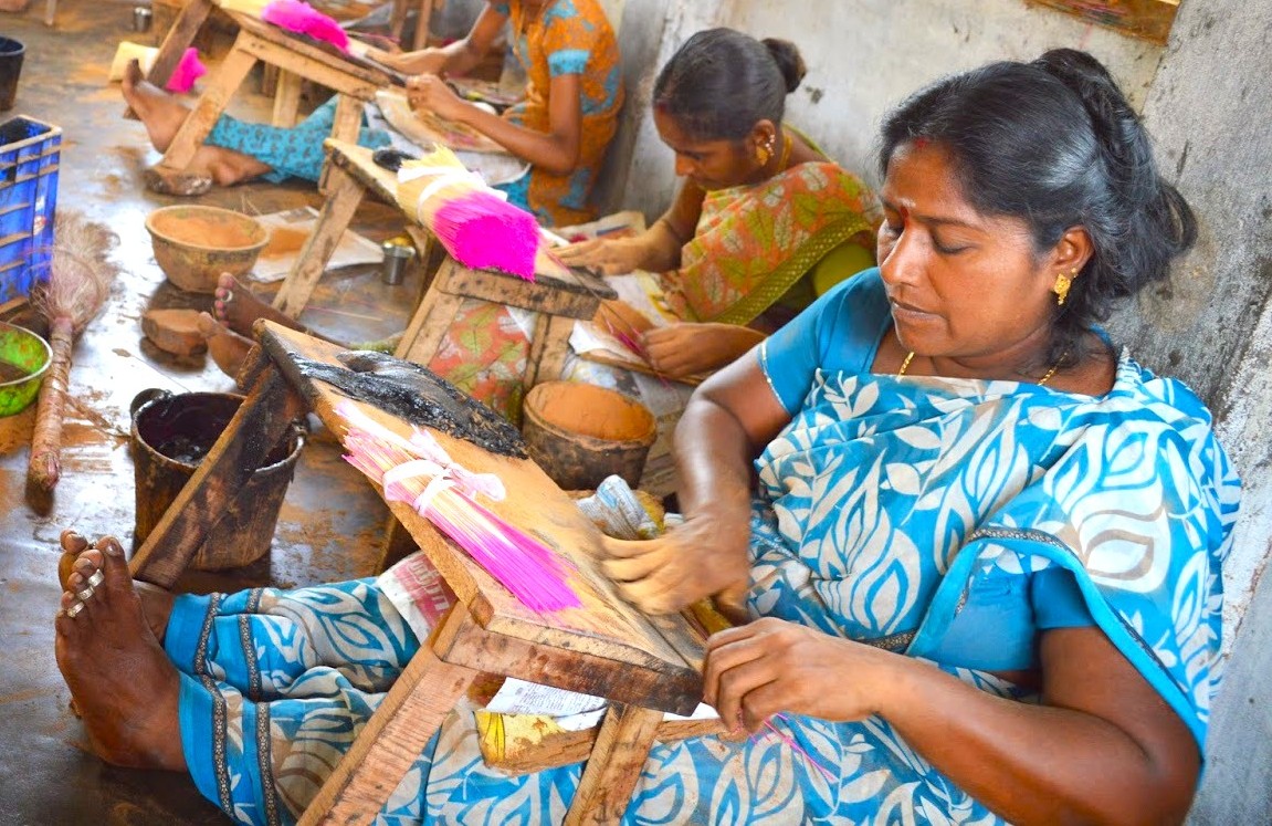“Artisan women meticulously handcraft vibrant incense sticks in a communal Mysore workshop, reflecting Karnataka heritage in Mysore oils and incense production, preserving India aromatic heritage.”