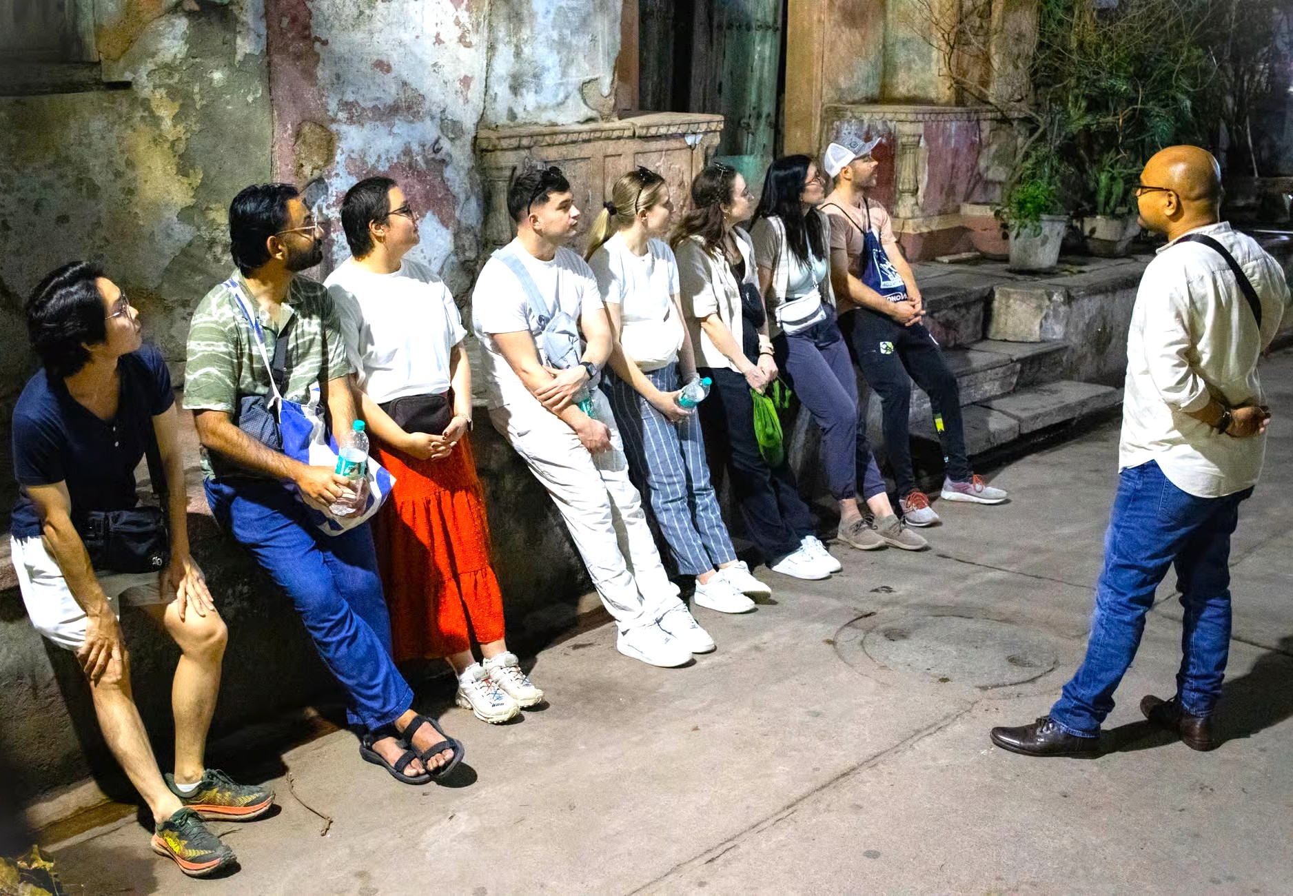A tour guide briefs tourists in Delhi, India, during a city tour that often includes India Gate, the Red Fort, and UNESCO sites Humayun's Tomb and Qutub Minar.