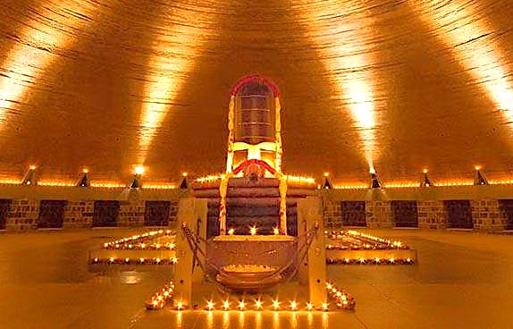 Interior of Isha Temple in Coimbatore, Tamil Nadu, India showcasing a radiant throne surrounded by candles, golden lighting, and reflective ambiance emphasizing spiritual ceremony significance. Interior of Isha Temple in Coimbatore, Tamil Nadu, India showcasing a radiant throne surrounded by candles, golden lighting, and reflective ambiance emphasizing spiritual ceremony significance.