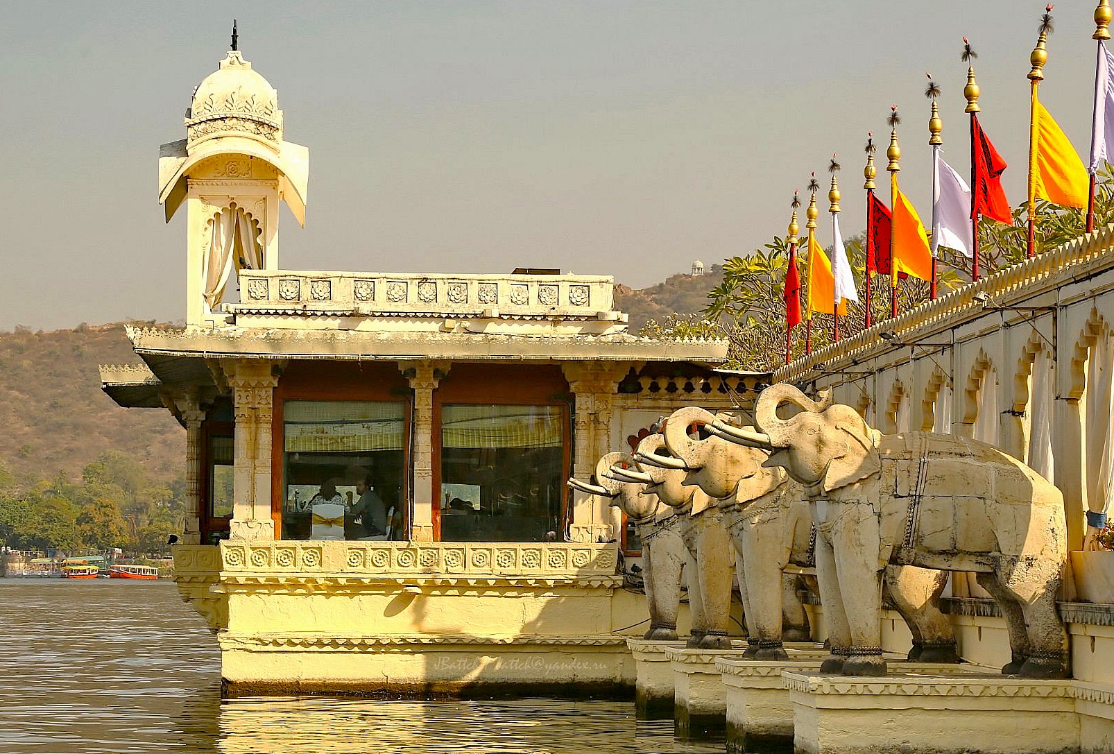 “Ornate marble elephant fountains at Jag Mandir on Lake Pichola in Udaipur, Rajasthan, India showcase exquisite Rajput-Mughal architecture, colorful flags, serene water reflections, historic grandeur, unique cultural heritage tourism experiences.”  “Ornate marble elephant fountains at Jag Mandir on Lake Pichola in Udaipur, Rajasthan, India showcase exquisite Rajput-Mughal architecture, colorful flags, serene water reflections, historic grandeur, unique cultural heritage tourism experiences.”