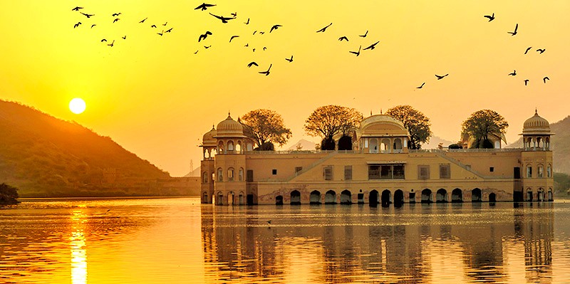 “Sunset view of Jal Mahal palace floating on Man Sagar Lake in Jaipur, Rajasthan, India, showcasing majestic ornate Rajput architecture reflected on tranquil waters with migratory birds amid Aravalli foothills.”