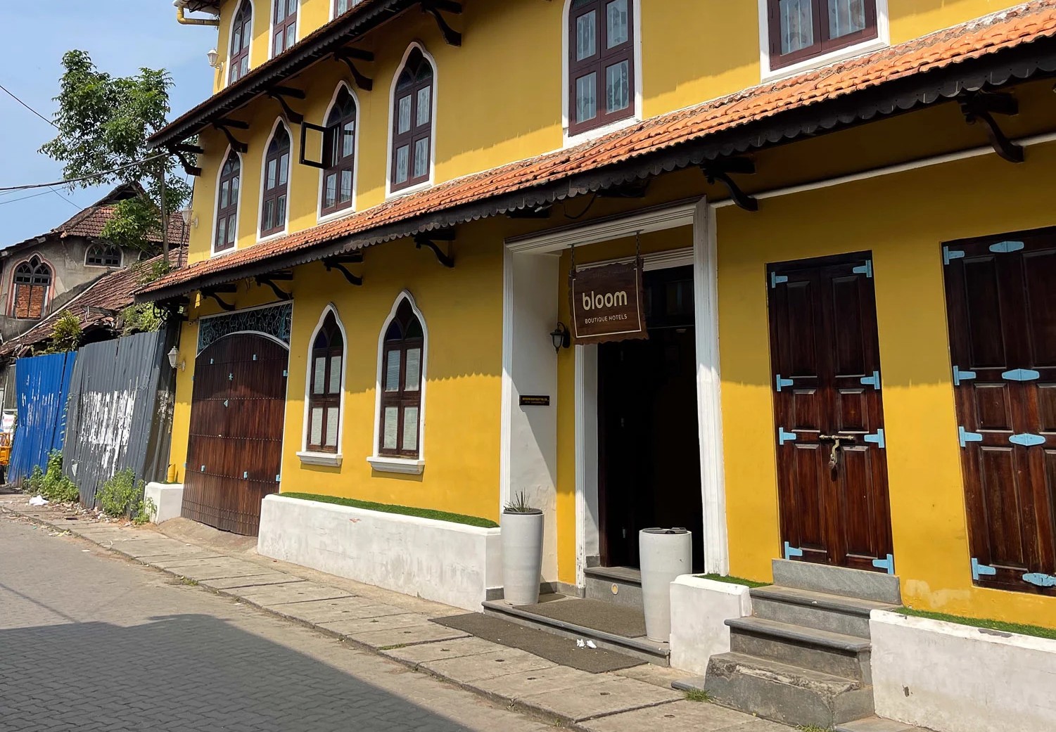 Vibrant yellow facade of Bloom Boutique Hotel in Fort Kochi complements nearby Kerala Folklore Museum Kochi, South India, Kerala, showcasing colonial architectural details, artisanal signage, arched windows, and tourism appeal. Vibrant yellow facade of Bloom Boutique Hotel in Fort Kochi complements nearby Kerala Folklore Museum Kochi, South India, Kerala, showcasing colonial architectural details, artisanal signage, arched windows, and tourism appeal.