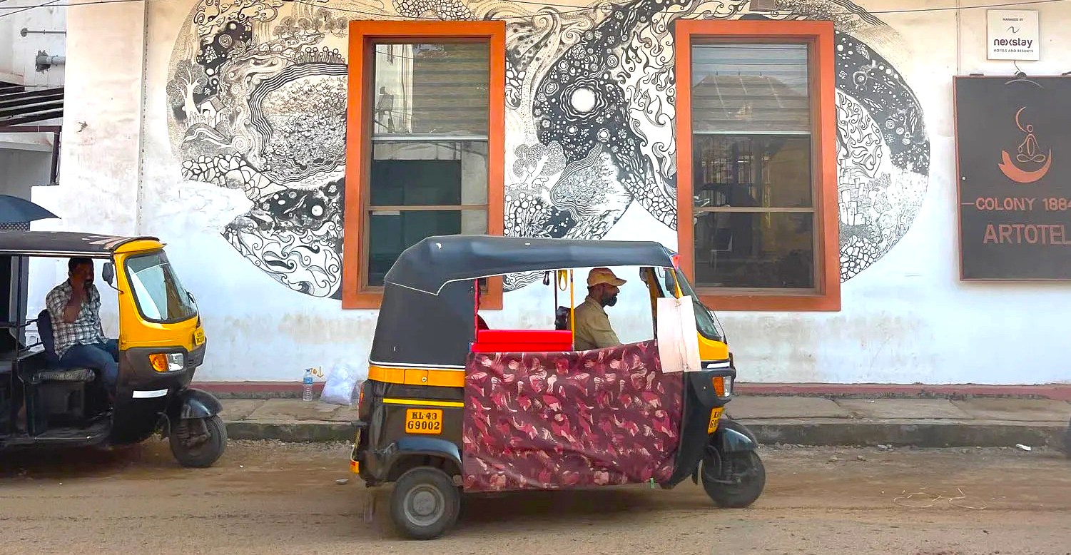 Colorful auto rickshaws navigate historic Fort Kochi streets in South India, passing intricate urban murals near the Kerala Folklore Museum Kochi, blending traditional transport, cultural art, and local heritage sightseeing. Colorful auto rickshaws navigate historic Fort Kochi streets in South India, passing intricate urban murals near the Kerala Folklore Museum Kochi, blending traditional transport, cultural art, and local heritage sightseeing.