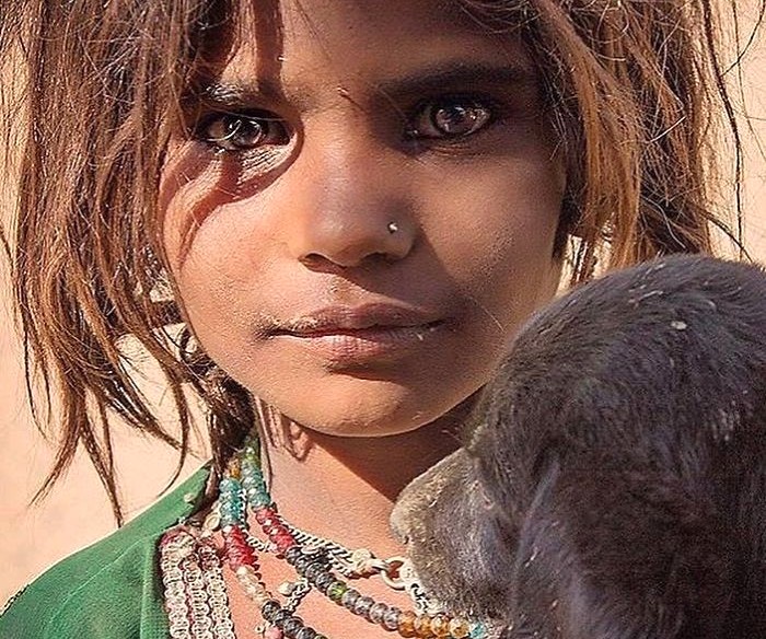 Close-up portrait of a young child in Jodhpur, the Blue City of Rajasthan, India, tenderly holding a goat against a sunlit Thar Desert backdrop, capturing rural life and authentic local compassion. Close-up portrait of a young child in Jodhpur, the Blue City of Rajasthan, India, tenderly holding a goat against a sunlit Thar Desert backdrop, capturing rural life and authentic local compassion.