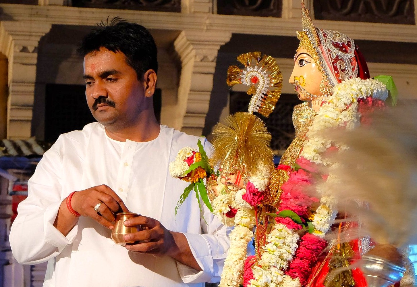 An Indian priest performs a spiritual ritual with a goddess idol, adorned in flowers, in Jodhpur, Rajasthan, India—an iconic city in the Thar Desert known as the blue city. An Indian priest performs a spiritual ritual with a goddess idol, adorned in flowers, in Jodhpur, Rajasthan, India—an iconic city in the Thar Desert known as the blue city.