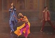Three dancers performing on stage in vibrant traditional costumes at Kalakriti Cultural Convention Centre, Agra.