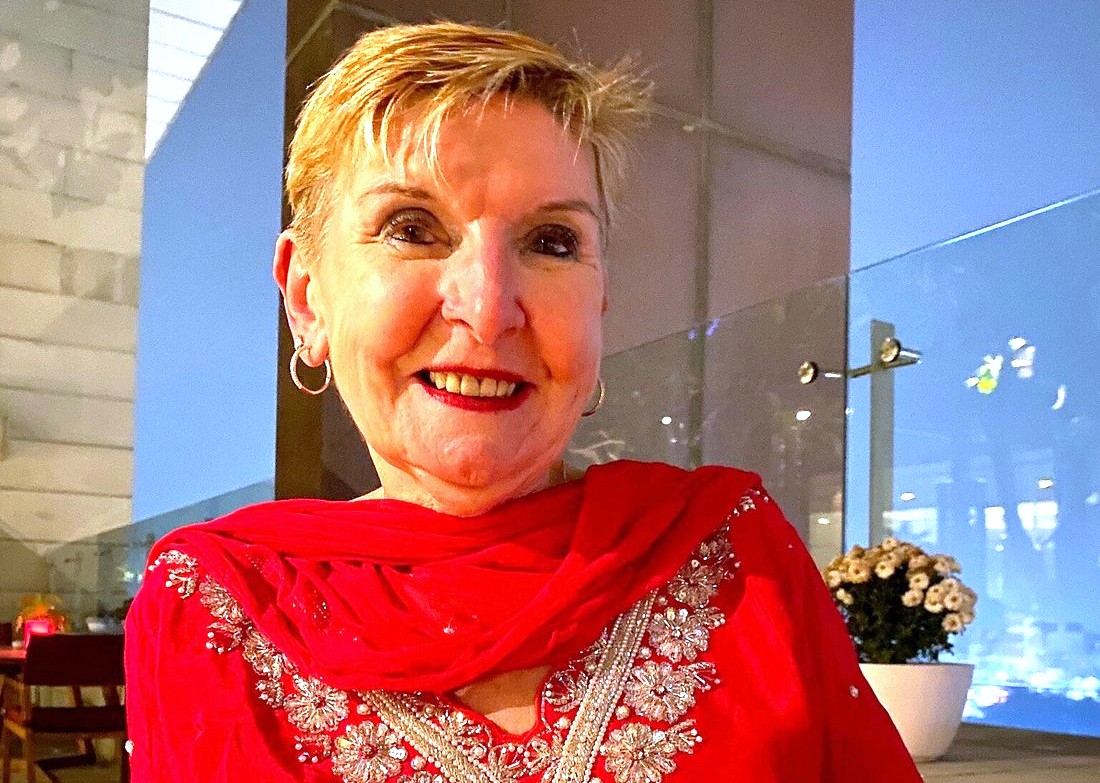 A tourist in red attire enjoys Delhi, India, home to Kamani Auditorium, an international performance centre, and UNESCO sites like Humayun's Tomb, the Red Fort, and Qutub Minar.