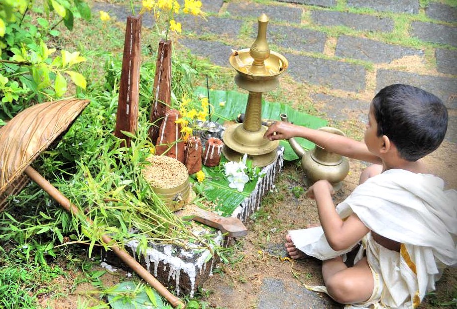 Young boy performs traditional Hindu lamp offering in vibrant South India courtyard, showcasing devotional ritual heritage that includes Mysore, Hampi, Bangalore, Madurai culture and spirituality.