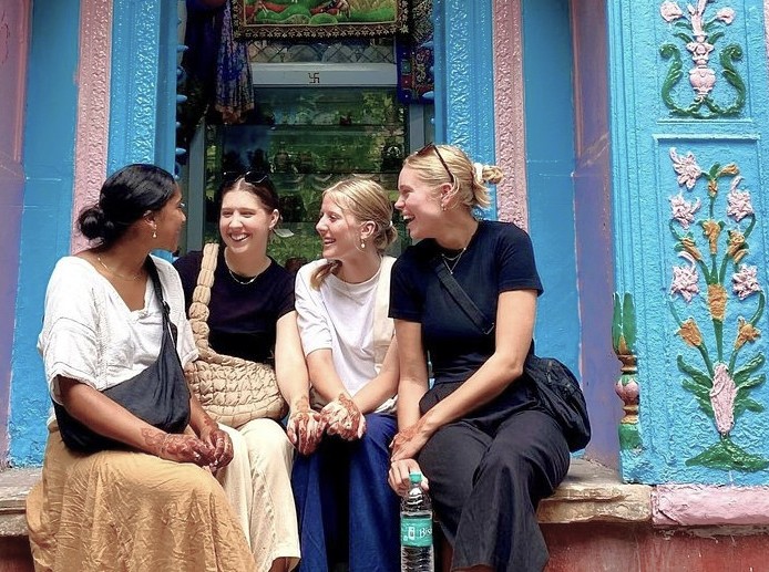 Four tourists adorned with henna share laughter on vibrant heritage steps, showcasing Karnataka culture in South India, includes Mysore, Hampi, Bangalore architectural motifs and design. Four tourists adorned with henna share laughter on vibrant heritage steps, showcasing Karnataka culture in South India, includes Mysore, Hampi, Bangalore architectural motifs and design.