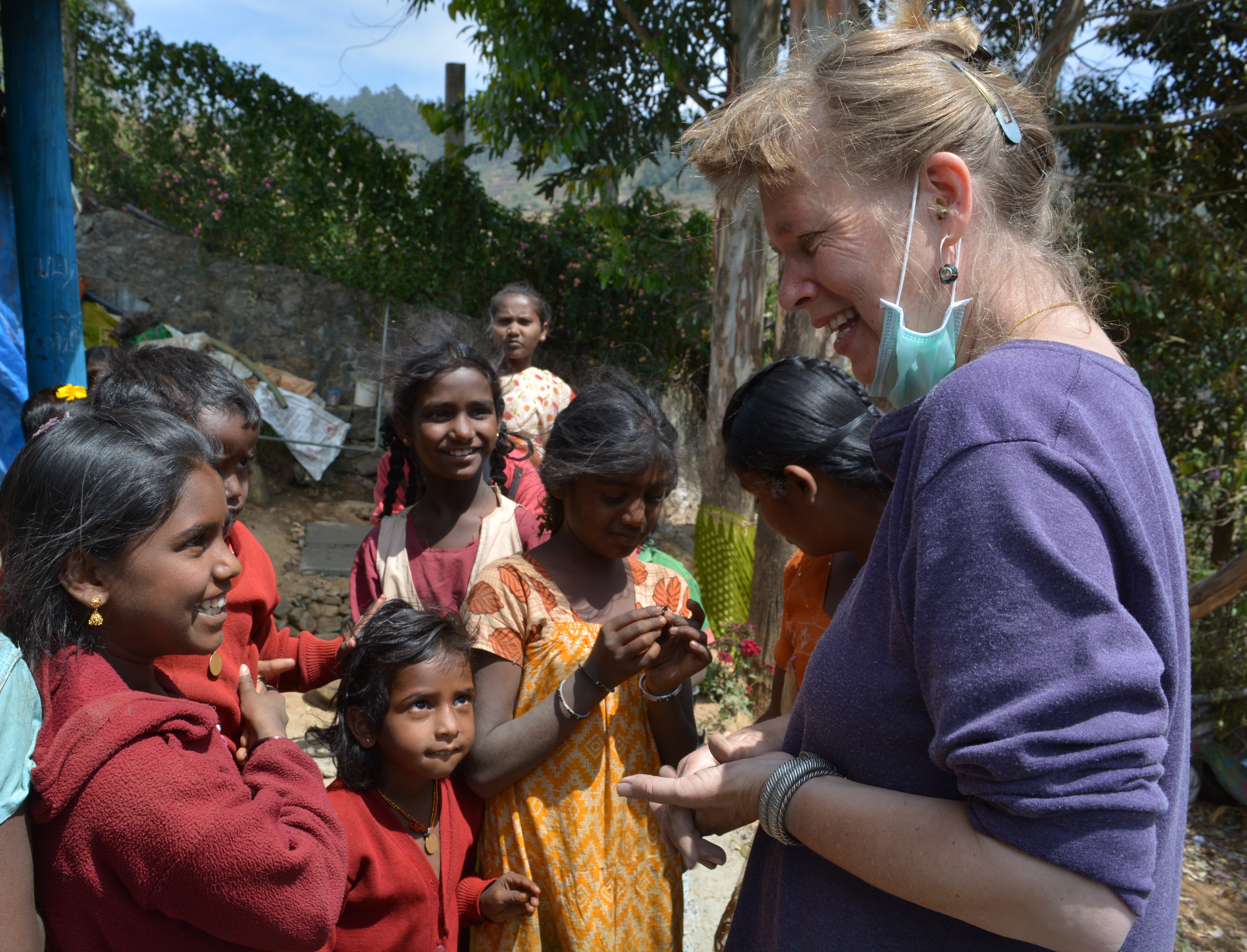 A volunteer interacting with a group of smiling children outdoors in Kathmandu, Nepal. A volunteer interacting with a group of smiling children outdoors in Kathmandu, Nepal.