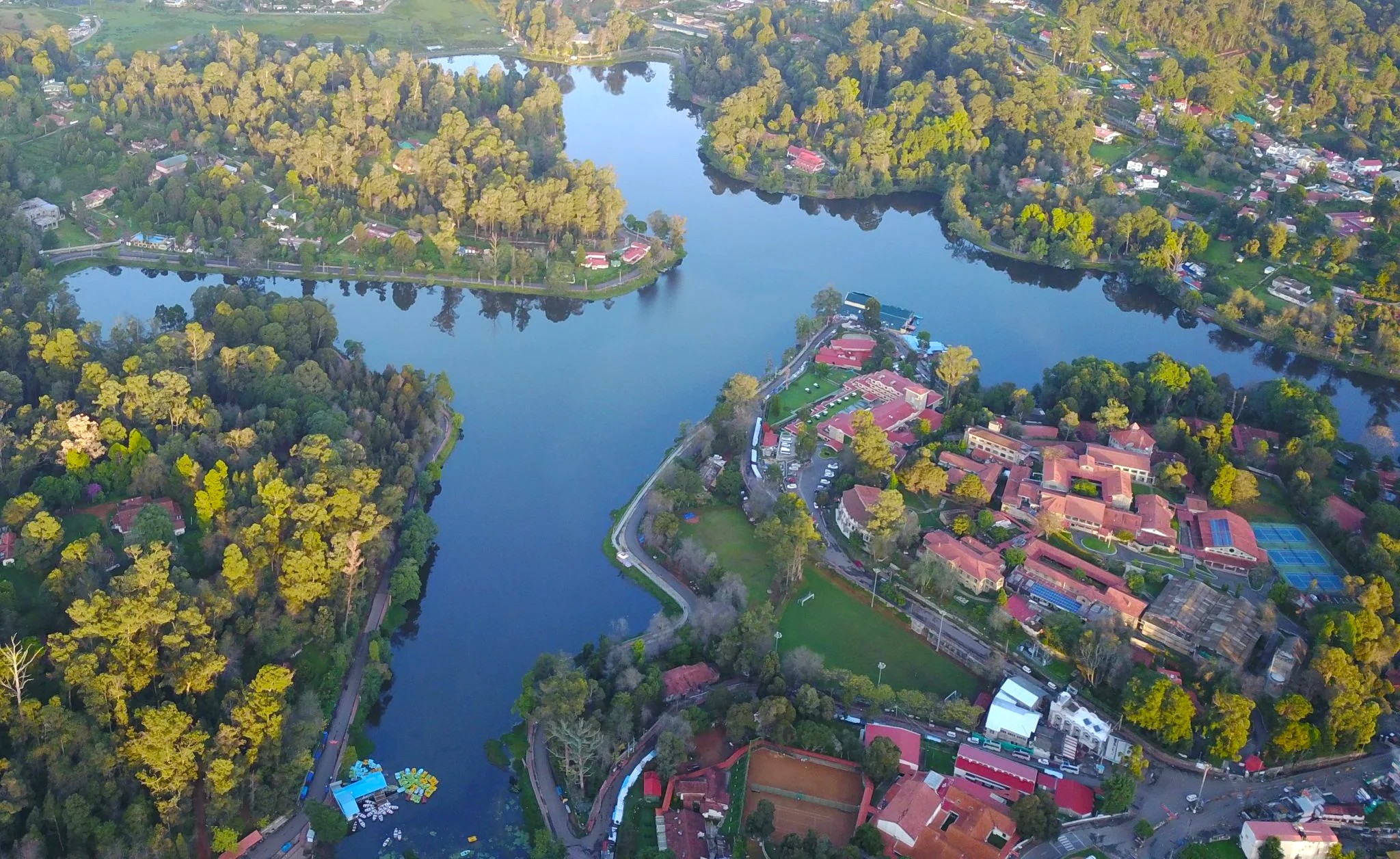 Spectacular aerial view of Kodai Lake Kulam nestled in Kodaikanal’s Palani Hills, Tamil Nadu, South India, surrounded by lush forests, residential retreats and recreational pathways.