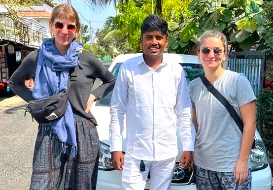 Three smiling travelers stand before a white vehicle near Kodai Lake Kulam in Kodaikanal’s Palani Hills, Tamil Nadu, South India, capturing a memorable lakeside adventure.