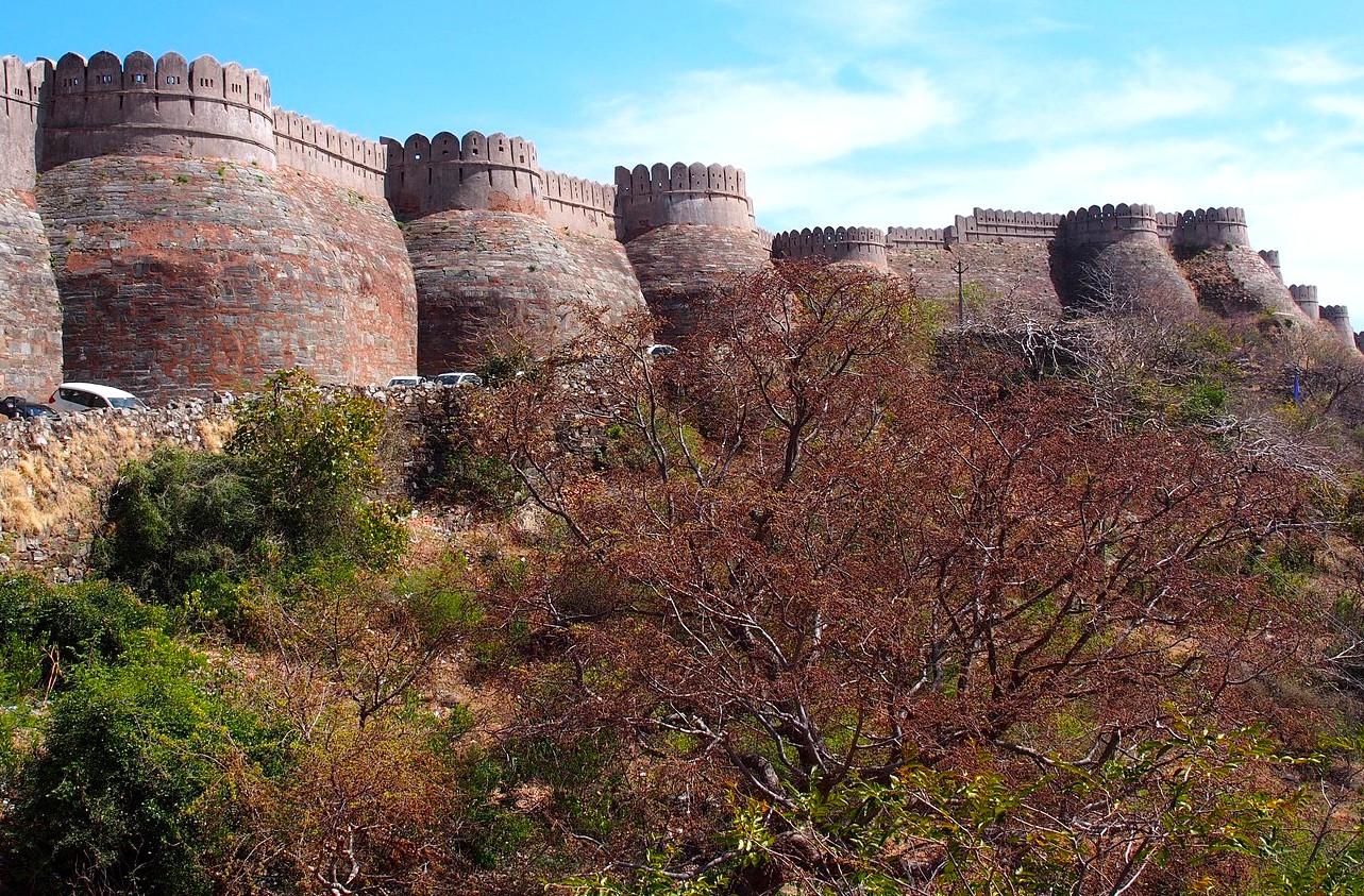 Perched atop the Aravali Hills near Udaipur and Jodhpur in Rajasthan, India, Kumbhalgarh Fort showcases imposing medieval stone ramparts, sweeping hillside views, native scrub vegetation, and parking at its base. Perched atop the Aravali Hills near Udaipur and Jodhpur in Rajasthan, India, Kumbhalgarh Fort showcases imposing medieval stone ramparts, sweeping hillside views, native scrub vegetation, and parking at its base.
