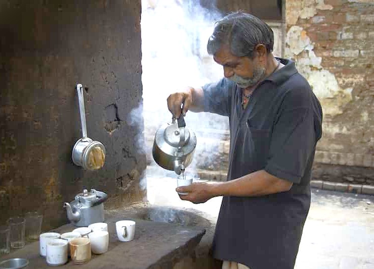 An elderly local in Udaipur’s Lake Pichola pours steaming chai from a kettle, savoring authentic Rajasthan tea on a serene Shikara boat tour in India’s romantic palace-city with iconic vistas. An elderly local in Udaipur’s Lake Pichola pours steaming chai from a kettle, savoring authentic Rajasthan tea on a serene Shikara boat tour in India’s romantic palace-city with iconic vistas.