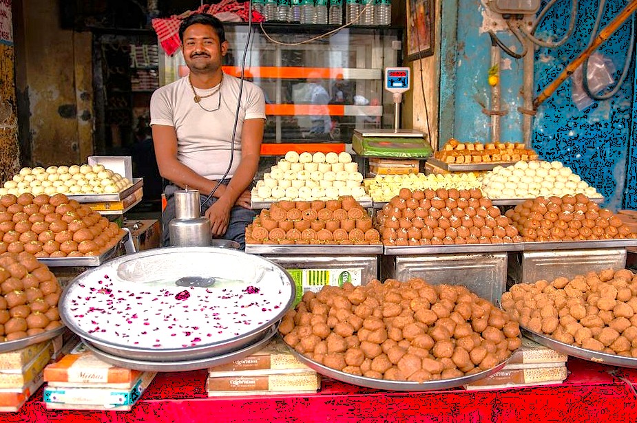 Enjoying local sweets is a highlight of a road trip to Unesco Hampi in India, a journey connecting wonders like the Lepakshi hanging pillar and Hampi's ancient queens baths.