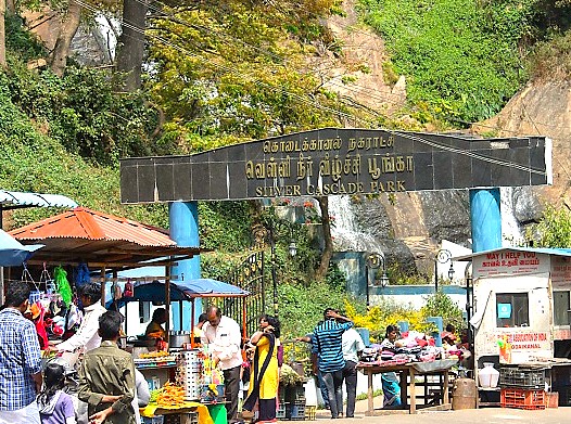 A bustling roadside food stop at Silver Cascade Park on the scenic Madurai to Munnar road trip in Tamil Nadu, India, a route that travels through the lush UNESCO Western Ghats.