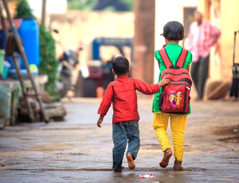 Two young Indian children walk home from school in Karnataka, a scene of daily life near the Mallikarjuna temple in Badami and the Pattadakal-UNESCO heritage site. Two young Indian children walk home from school in Karnataka, a scene of daily life near the Mallikarjuna temple in Badami and the Pattadakal-UNESCO heritage site.