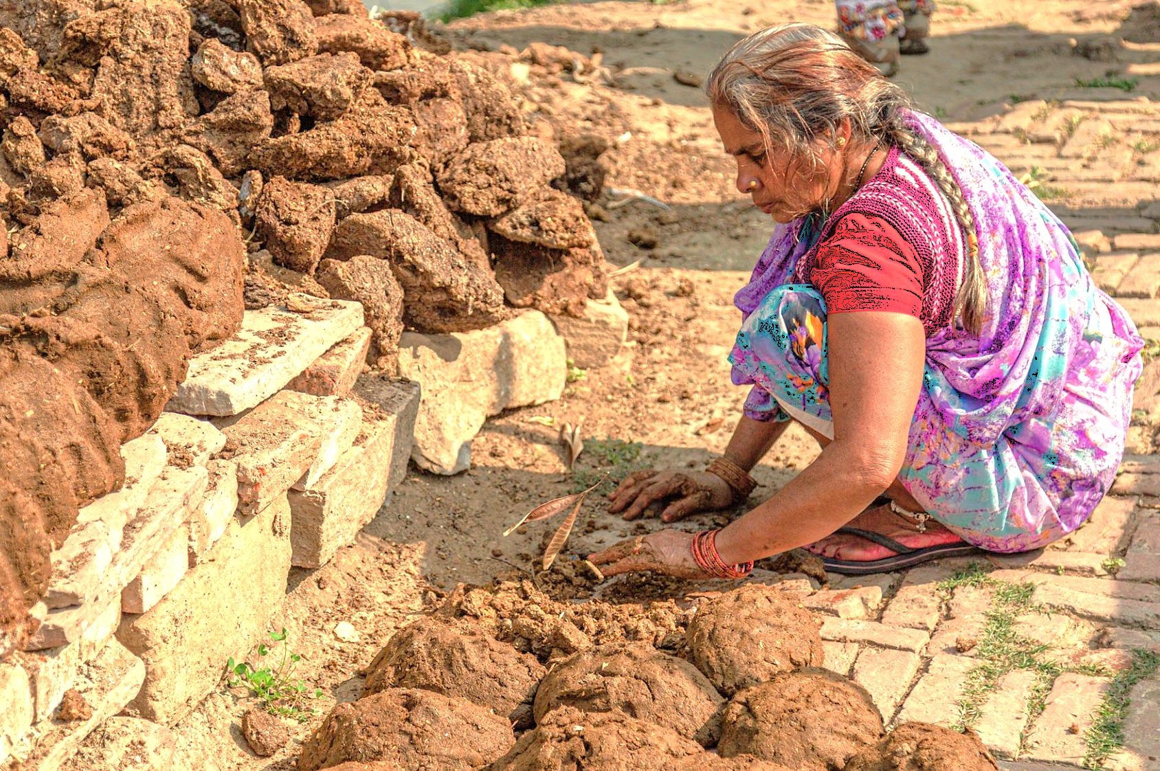 A local woman prepares traditional cow dung fuel cakes in a village near the Meguti Temple at Aihole, Karnataka, India, close to the Badami temples and Pattadakal UNESCO site. A local woman prepares traditional cow dung fuel cakes in a village near the Meguti Temple at Aihole, Karnataka, India, close to the Badami temples and Pattadakal UNESCO site.