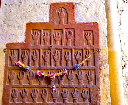 Carved handprints commemorating women who died on the funeral pyre adorn a sandstone wall at Mehrangarh Fort, Jodhpur, Rajasthan, India, reflecting historic timeless cultural ritual significance and intricate architectural detail. Carved handprints commemorating women who died on the funeral pyre adorn a sandstone wall at Mehrangarh Fort, Jodhpur, Rajasthan, India, reflecting historic timeless cultural ritual significance and intricate architectural detail.