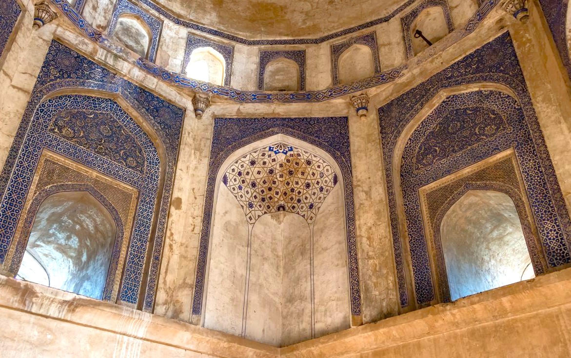 Intricate blue and white tile mosaics decorate arched niches and domed windows inside a 14th-century mosque hall at Mehrauli Archaeological Park in Delhi, India, showcasing exquisite Islamic craftsmanship and heritage. Intricate blue and white tile mosaics decorate arched niches and domed windows inside a 14th-century mosque hall at Mehrauli Archaeological Park in Delhi, India, showcasing exquisite Islamic craftsmanship and heritage.