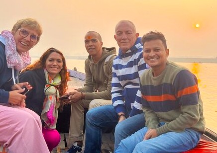 Tourists with Mehrotra-silks build a friendly relationship with local guides on a sunrise boat tour in Varanasi, India, experiencing the culture near the Sarnath UNESCO site.