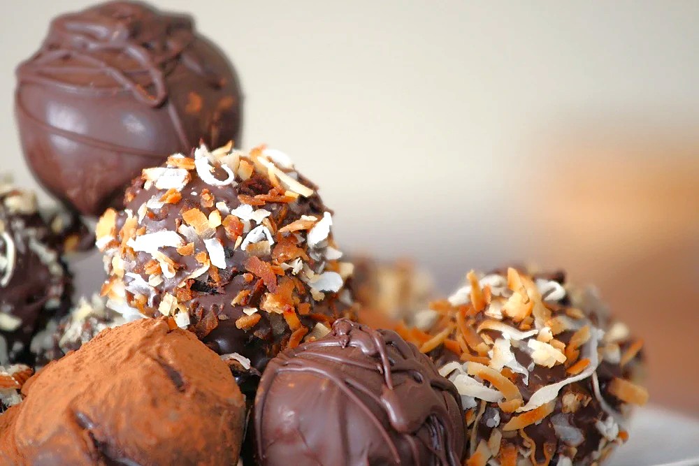 Assorted Moddy’s Chocolate truffles topped with toasted coconut and cocoa powder on a platter in Ooty, Tamil Nadu, Southern India, highlighting artisanal luxury dessert flavors. Assorted Moddy’s Chocolate truffles topped with toasted coconut and cocoa powder on a platter in Ooty, Tamil Nadu, Southern India, highlighting artisanal luxury dessert flavors.