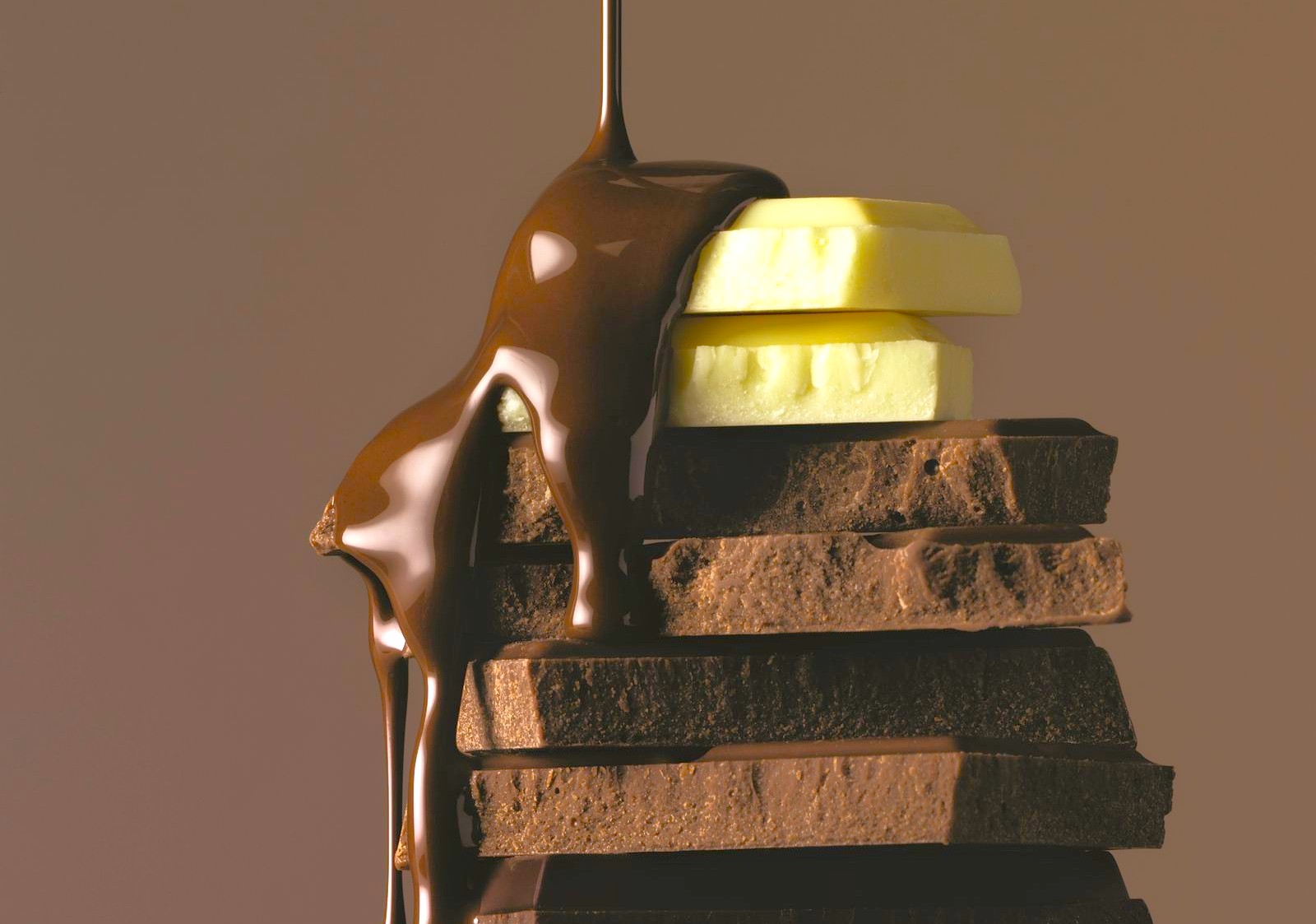 Decadent artisanal chocolate dessert topped with creamy cheese slices and cascading melted chocolate overlooking the picturesque lush tea plantation hills of Munnar, Kerala, Southern India.