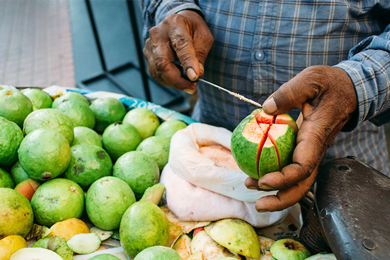 Local vendor skillfully peels fresh guava at vibrant Munnar fruit market in Kerala, Southern India, showcasing sustainable agriculture, traditional market culture, juicy tropical fruit delight.