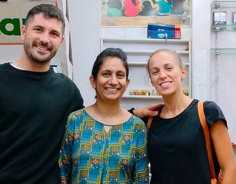 Three smiling tourists explore a vibrant historic shop near the Murugan Temple in Palani Hills, Kodaikanal, Tamil Nadu, South India, discovering local handicrafts, cultural treasures, and unforgettable cherished travel memories.