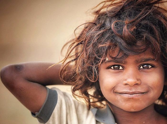 Portrait of a smiling local child at Nagaur Fort in Rajasthan, India, capturing expressive dark eyes and tousled hair against sunlit sandstone walls bordering the Thar Desert, evoking cultural warmth. Portrait of a smiling local child at Nagaur Fort in Rajasthan, India, capturing expressive dark eyes and tousled hair against sunlit sandstone walls bordering the Thar Desert, evoking cultural warmth.