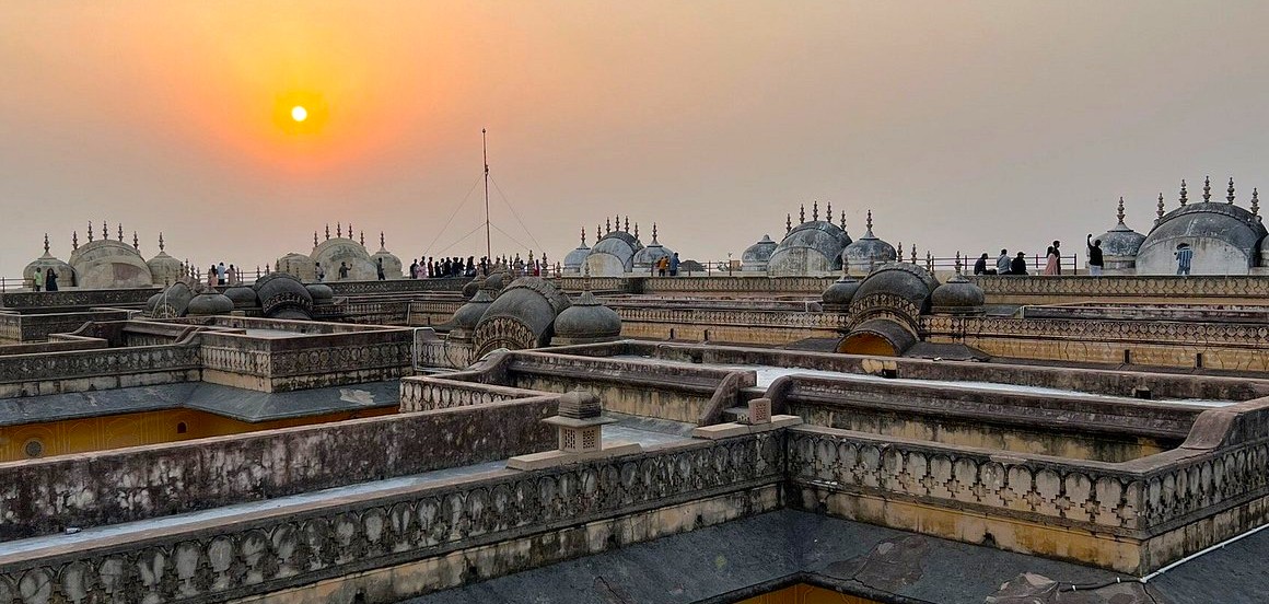 Panoramic sunset view of Nahargarh Fort’s historic ramparts overlooking Jaipur cityscape in Rajasthan, India, where ancient Mughal-style architecture meets vibrant tourist activity, offering cultural heritage exploration and stunning photo opportunities.