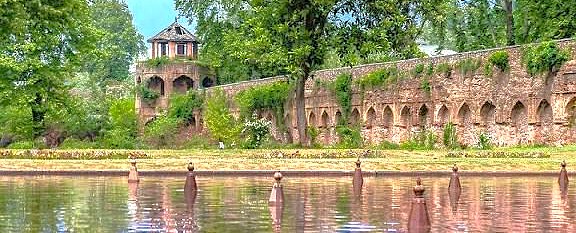 Scenic view from a Nehru Ghat shikara boat tour on Nigeen Lake, showing historic Mughal gardens, a top attraction in Srinagar, Jammu and Kashmir, India.