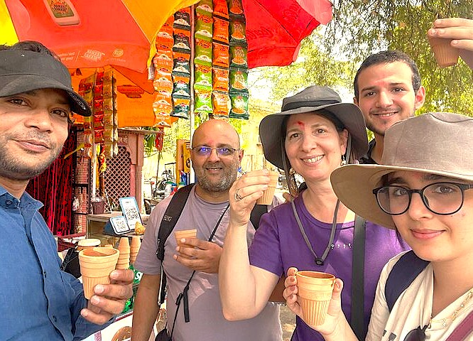 Smiling tourists enjoy local street chai near Pari Mahal, embracing the hospitality and vibrant culture of Srinagar, a UNESCO Creative Arts city in Jammu and Kashmir, India.