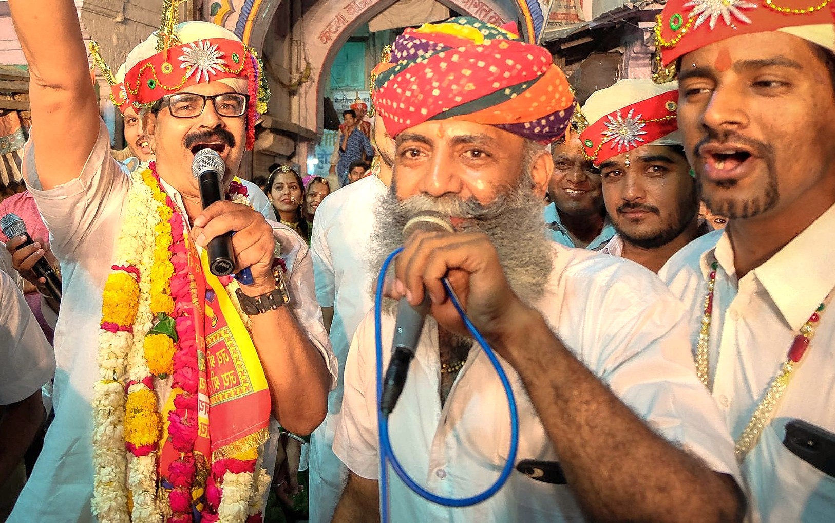 Rajasthani speakers in vibrant turbans and garlands address a festive crowd at the ornate Patrika Gate of Jaipur, Rajasthan, India, celebrating traditional culture, community unity, heritage fairs and colorful festivities.