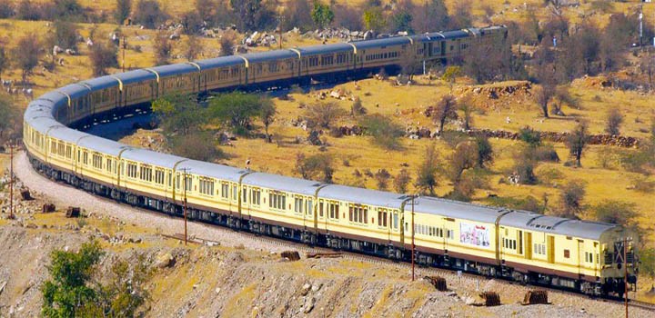 Experience a railway journey from Delhi to Bikaner into the Thar Desert in Rajasthan, India, aboard a yellow train weaving through semi arid landscapes, rocky terrain, and vibrant cultural vistas.