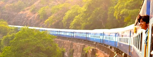 “Blue passenger train winds through verdant Western Ghats on the historic Mumbai–Aurangabad railway journey in India, near UNESCO-listed Elephanta Caves, offering breathtaking vistas en route to Elora and Ajanta Caves.”