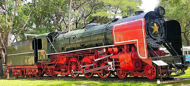 Green and red vintage steam locomotive with star emblem displayed outdoors at Mysore Railway Museum, Karnataka, India, surrounded by lush grass and trees under bright sunlight. Green and red vintage steam locomotive with star emblem displayed outdoors at Mysore Railway Museum, Karnataka, India, surrounded by lush grass and trees under bright sunlight.