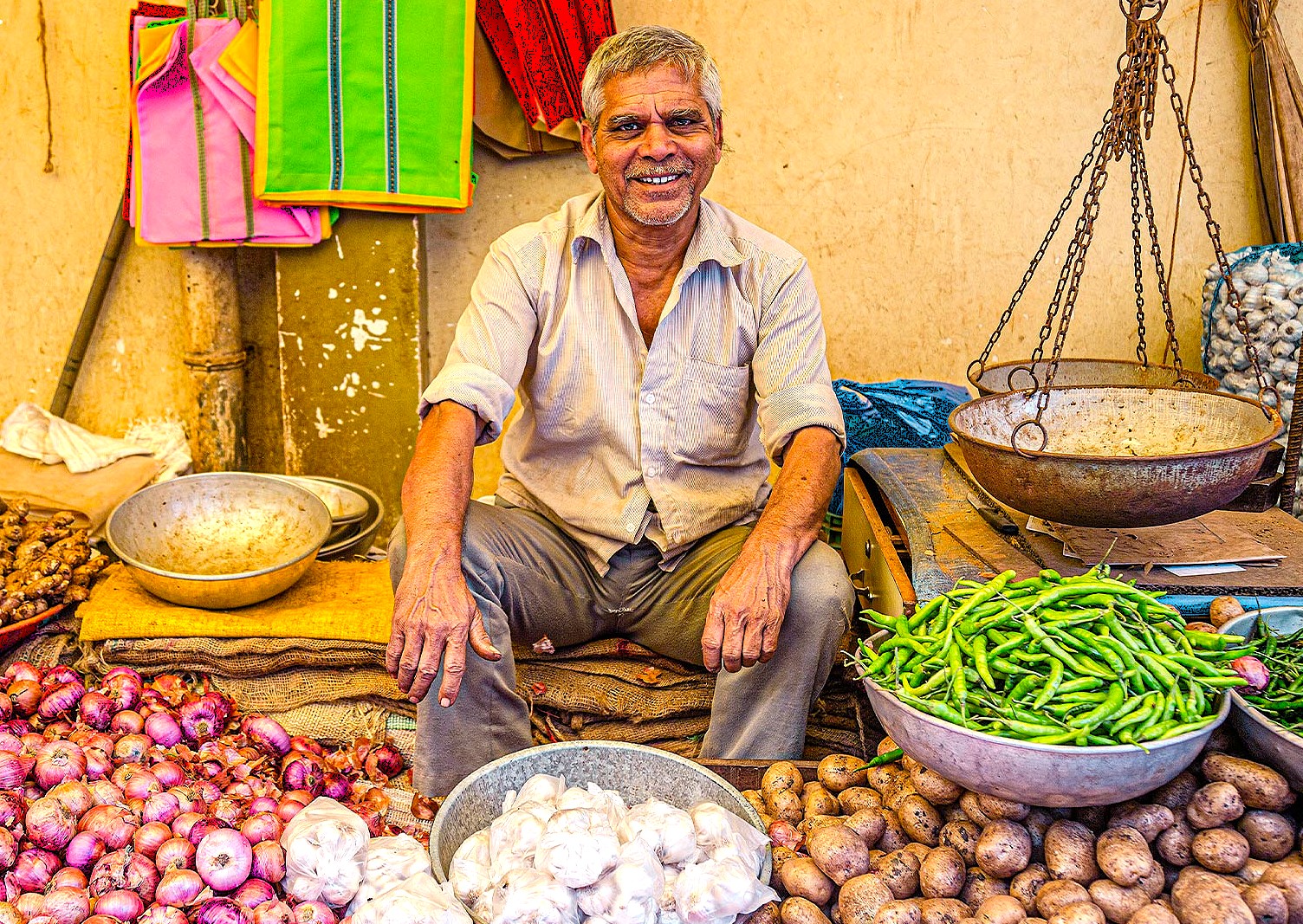 A smiling local vegetable vendor sells fresh produce like garlic and onions at a market near Rajon ki Baoli in Delhi, India, a historic area close to UNESCO sites like Qutb Minar, UNESCO Red Fort, and UNESCO Humayun's Tomb. A smiling local vegetable vendor sells fresh produce like garlic and onions at a market near Rajon ki Baoli in Delhi, India, a historic area close to UNESCO sites like Qutb Minar, UNESCO Red Fort, and UNESCO Humayun's Tomb.