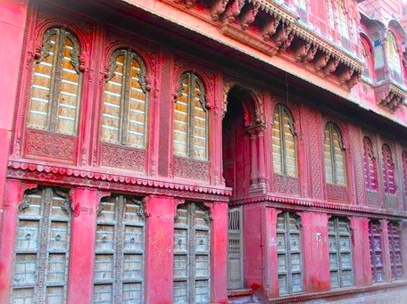 Vibrant red plastered Rampura Havelis in Bikaner, Rajasthan, showcase intricate ornate wooden jharokhas and carved sandstone facades, embodying centuries-old traditional craftsmanship on the edge of India’s vast Thar Desert heritage. Vibrant red plastered Rampura Havelis in Bikaner, Rajasthan, showcase intricate ornate wooden jharokhas and carved sandstone facades, embodying centuries-old traditional craftsmanship on the edge of India’s vast Thar Desert heritage.