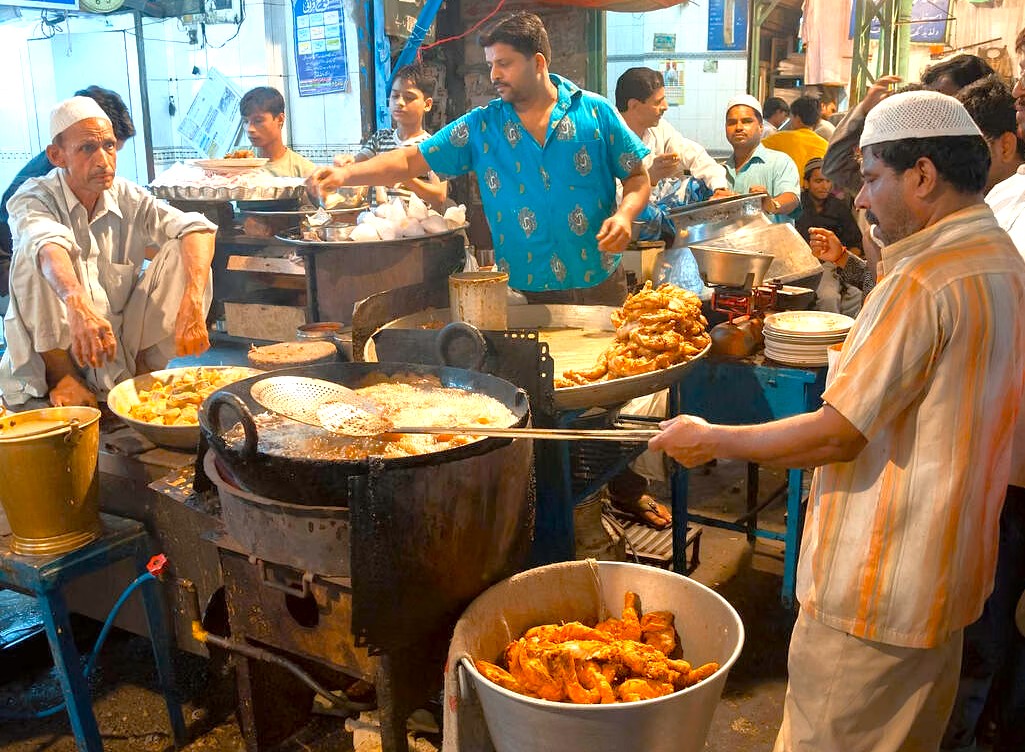 Street food vendors frying traditional snacks at a bustling stall near the Red Fort in Delhi, India, showcasing local cuisine, vibrant market atmosphere, cultural heritage, authentic flavors, lively street scene. Street food vendors frying traditional snacks at a bustling stall near the Red Fort in Delhi, India, showcasing local cuisine, vibrant market atmosphere, cultural heritage, authentic flavors, lively street scene.