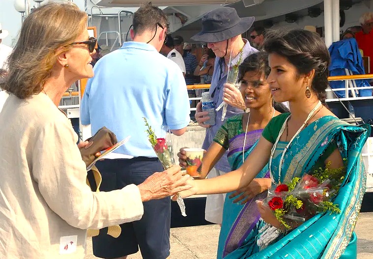 Local Indian women in traditional sarees extend a warm welcome with red roses to tourists visiting the Church of Saint Cajetan, part of the Old Goa Unesco churches in Goa, India. Local Indian women in traditional sarees extend a warm welcome with red roses to tourists visiting the Church of Saint Cajetan, part of the Old Goa Unesco churches in Goa, India.