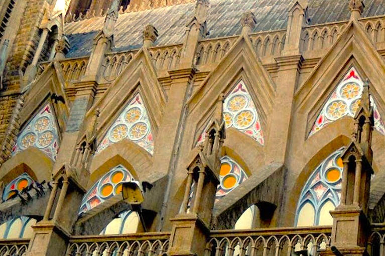 Discover the intricate Gothic facade of Saint Philomena’s Cathedral in Mysore, Karnataka, India, a majestic landmark between Bangalore and Coimbatore, with the illuminated Mysore Palace glowing nearby in the evening.