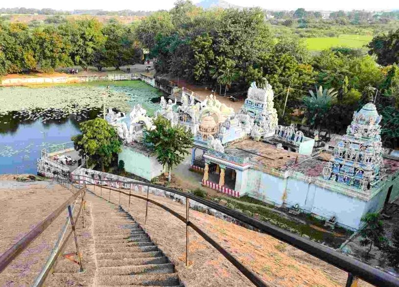 Panoramic view from stone steps overlooking a serene Hindu temple beside a lotus pond at Samarnar Hills in Madurai, Tamil Nadu, South India, showcasing Dravidian architecture and lush green surroundings. Panoramic view from stone steps overlooking a serene Hindu temple beside a lotus pond at Samarnar Hills in Madurai, Tamil Nadu, South India, showcasing Dravidian architecture and lush green surroundings.