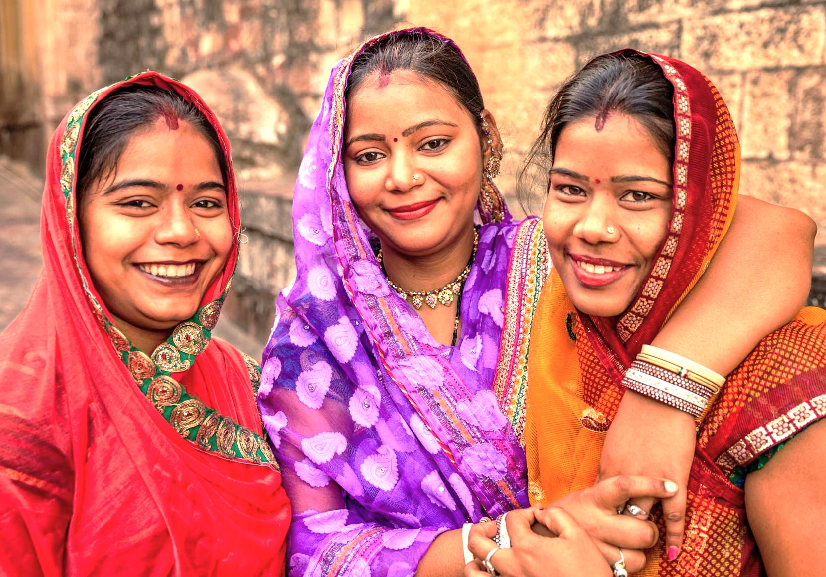 The warm relationship and friendship between three local women are captured at the Sarnath UNESCO site near Varanasi, India, reflecting the vibrant community spirit of the region.