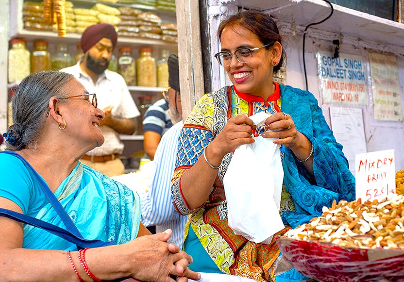 Local women enjoy authentic Indian culture, sharing smiles near a dry fruit stall, representing vibrant market interactions close to the UNESCO heritage site of Pattadakal, India. Local women enjoy authentic Indian culture, sharing smiles near a dry fruit stall, representing vibrant market interactions close to the UNESCO heritage site of Pattadakal, India.