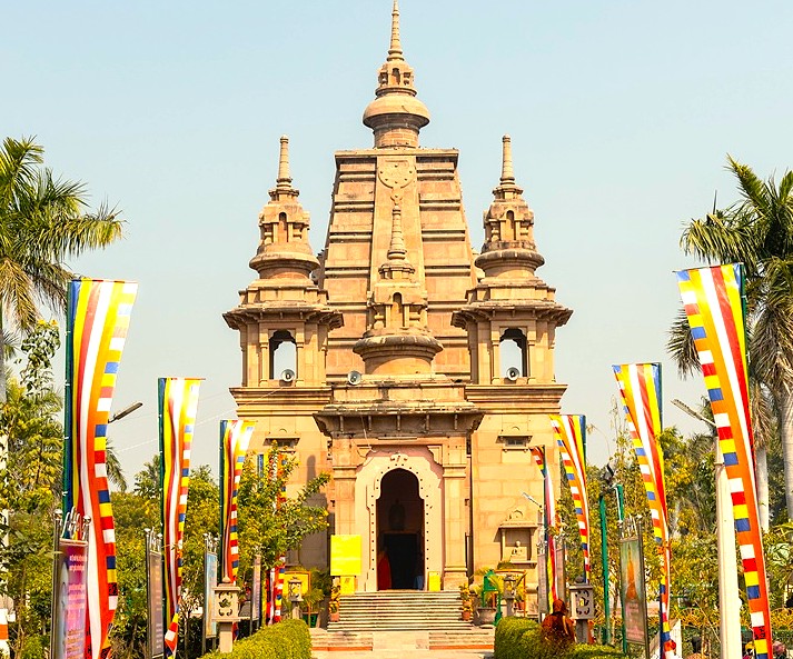 This modern temple at the Sarnath UNESCO site near Varanasi, India, illustrates the enduring relationship between contemporary faith and ancient Buddhist history, adorned with colorful prayer flags.