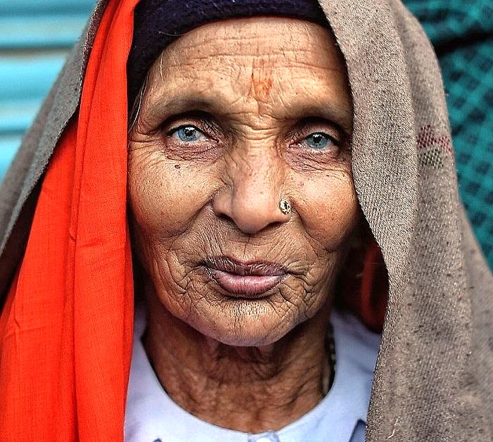 Portrait of elderly Rajasthani woman with blue eyes, nose ring, draped in shawls near Pushkar Savitri Temple in Ajmer, Rajasthan, India, between Jaipur and Agra en route to Taj Mahal.