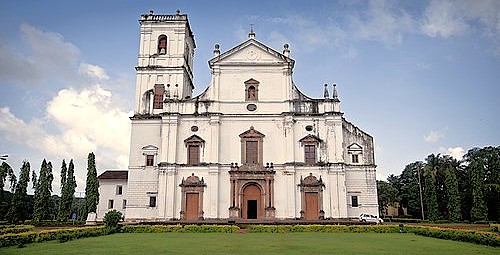 A bright day highlights the grand, whitewashed exterior of Se Cathedral, a famous landmark within the Unesco churches of Old Goa, Goa, India, set against a blue sky.