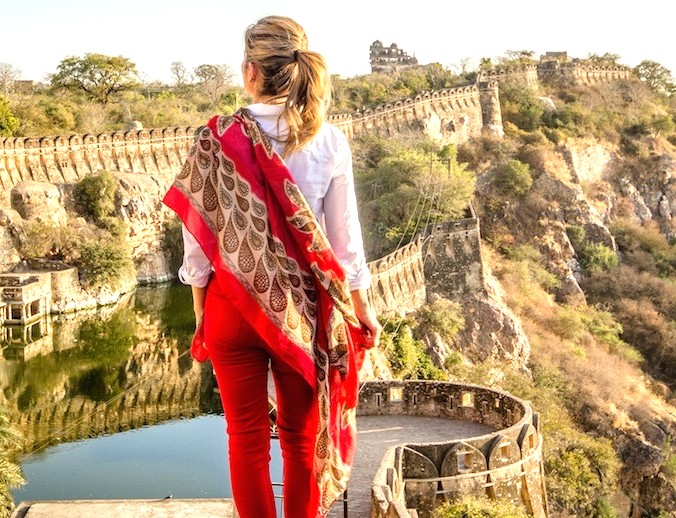 A tourist overlooks historic hilltop ruins and serene lake in Palani Hills at Kodaikanal, Tamil Nadu, South India, draped in vibrant, handwoven Shalimar Weaves scarf.